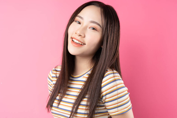 jong aziatisch vrouw poseren op roze achtergrond - Foto, afbeelding