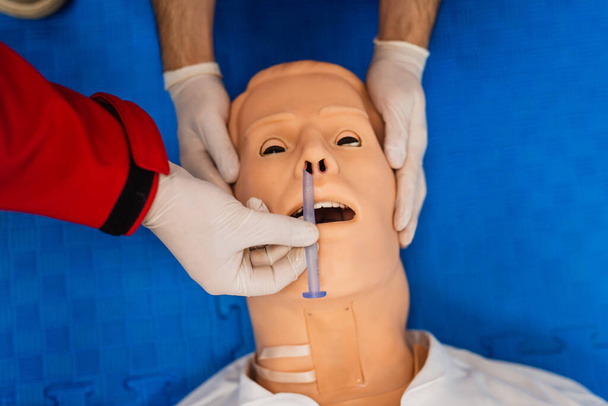 Top view of first aid training with a doll held by paramedics and a tube in the nose - Photo, Image