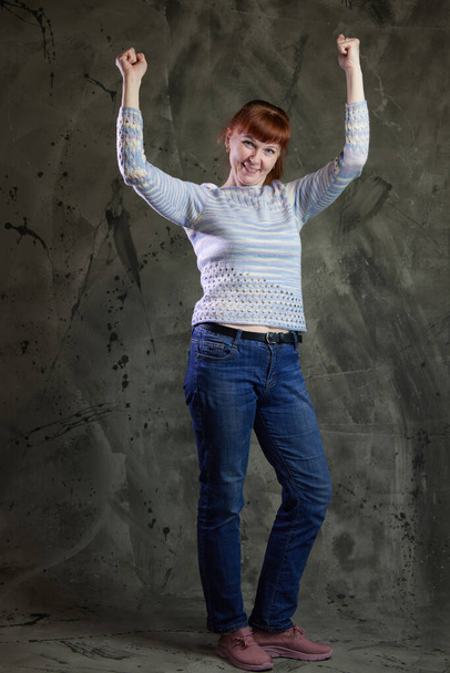 Portrait of Caucasian woman posing in full growth in jeans in studio on gray background. High resolution photos - Fotografie, Obrázek