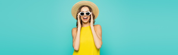 Happy woman in straw hat holding sunglasses isolated on blue, banner  - Fotó, kép