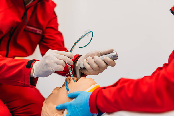 Training voor endotracheale intubatie met behulp van medische dummy. Paramedici in rode uniformen oefenen intubatie. - Foto, afbeelding