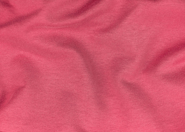 Рожева майка з тканини матової текстури вид зверху. Червоний кораловий трикотаж атласний фон. Модний колір тенденція жіночого одягу. Дизайн текстових знаків жіночого блогу. Жирні абстрактні шпалери текстильна поверхня
. - Фото, зображення