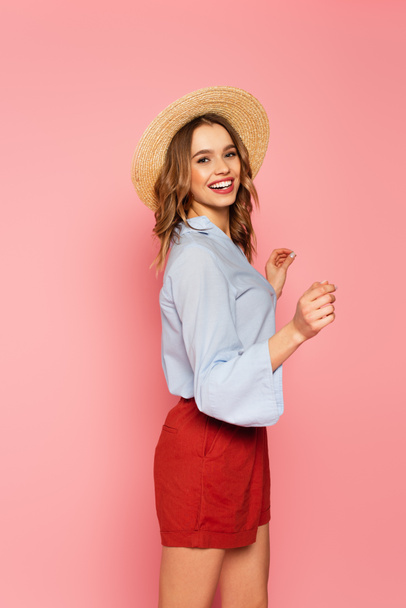 Stylish woman in straw hat dancing on pink background  - Foto, Imagem