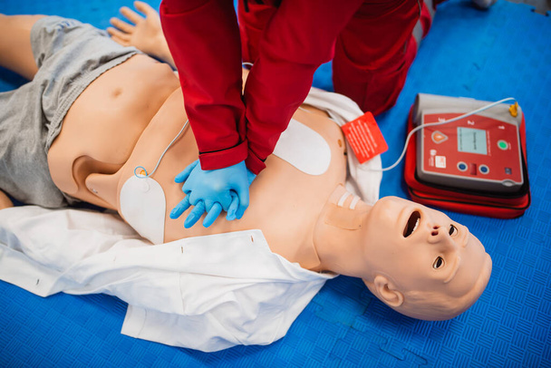 A man with blue rubber gloves practices giving artificial respiration to a doll. Exercise first aid - Photo, Image