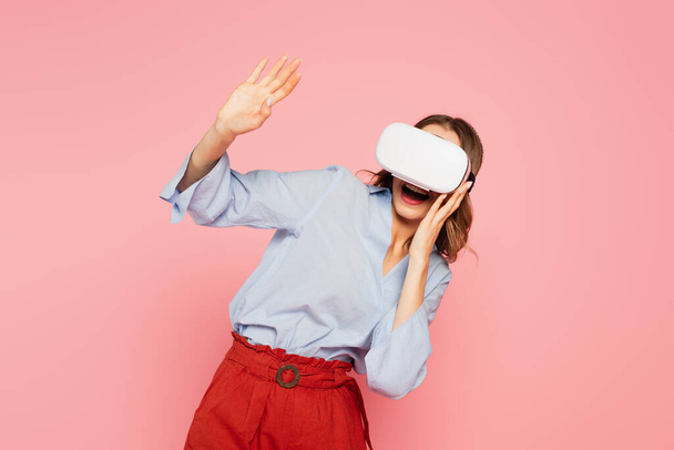 Excited woman in vr headset waving hand isolated on pink  - Foto, afbeelding