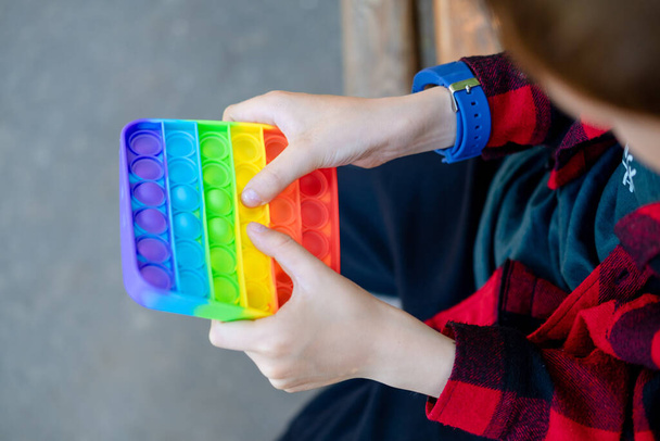 Pop it fidget toy in boy hand's. Colorful antistress kid's toy fidget. Trendy new toy. multicolored popit close-up - Foto, Imagen