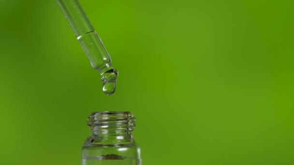 Goteo de aceite médico de la pipeta sobre fondo verde - Imágenes, Vídeo