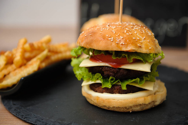 Tasty burger and french fries on black plate - Zdjęcie, obraz