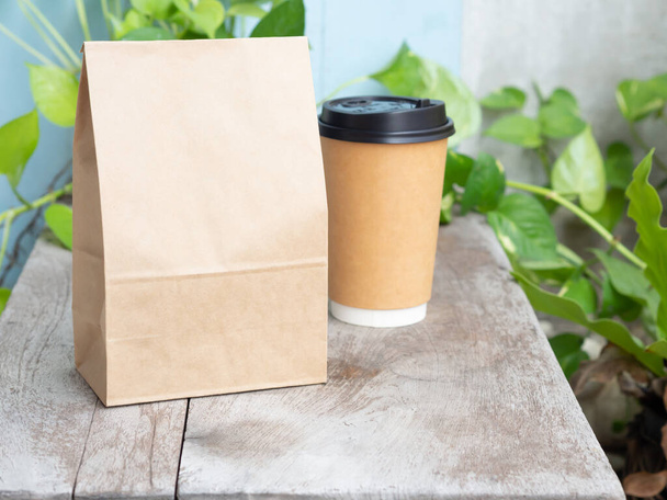Жареный кофе в бумажном пакете с чашкой на деревянном столе. Mouckup, шаблон с местом для копирования текста или логотипа - Фото, изображение