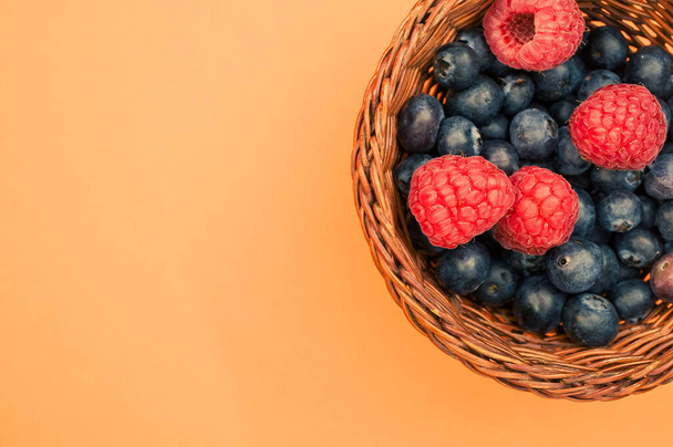 A top view of blueberries and raspberries in a basket - Foto, imagen