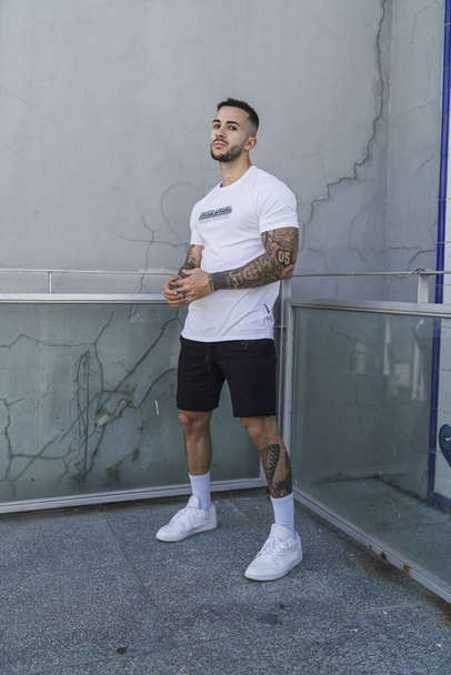 A young man with tattoos in cool casual style posing outdoors - Φωτογραφία, εικόνα