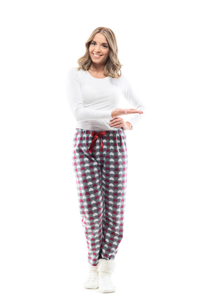 Happy confident pretty young woman in cozy pajama showing and presenting copy space. Full body length isolated on white background. - Foto, immagini