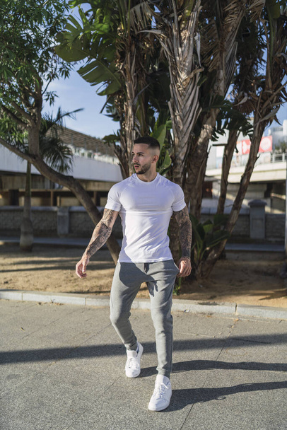 A young man with tattoos in cool casual style posing outdoors - Фото, зображення