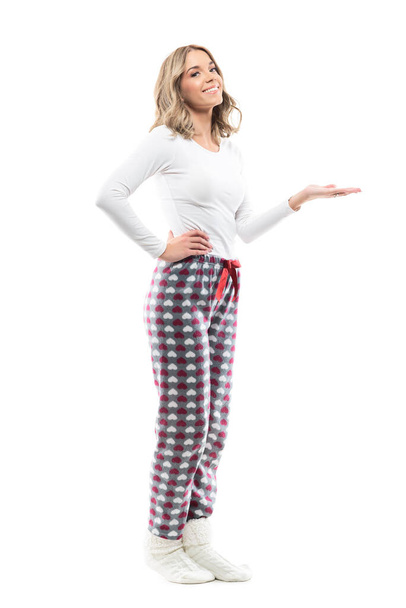Kaunis nuori onnellinen nainen pyjamassa esittelee avoimin käsin. Koko kehon pituus eristetty valkoisella pohjalla. - Valokuva, kuva
