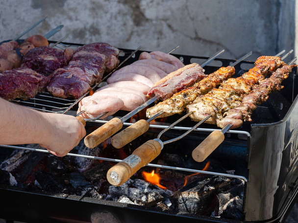 A person barbequing different types of meat - Foto, immagini
