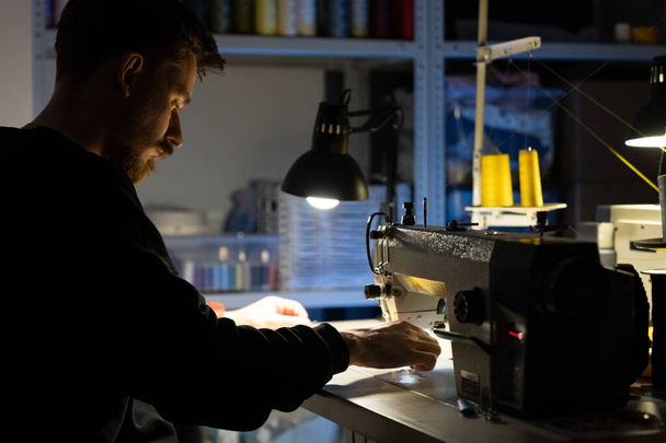 Hipster designer uomo cucire a macchina da cucire. Lavoro creativo in studio sartoriale o concetto di atelier - Foto, immagini