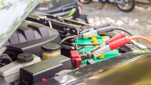 Sluiten Opladen autobatterij met elektriciteit via startkabels. - Foto, afbeelding