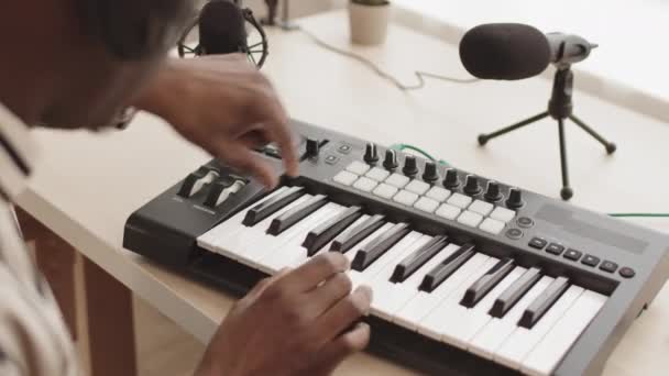 Вид сзади на неузнаваемого афроамериканца, играющего на синтезаторе midi-клавиатуры, создавая музыку в домашней студии - Кадры, видео