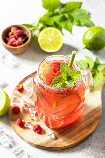 Frisdrank, gezonde drank. Verfrissende zomerglazen drinken frambozen met muntlimoen en ijs op een stenen tafel. - Foto, afbeelding
