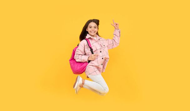 boldog gyermek lány viselni rózsaszín kockás ing ugrás iskola hátizsák, tele energiával. - Fotó, kép