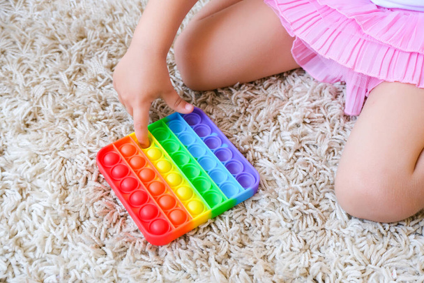 Cute faceless child playing with the Pop It fidget. Push pop bubble flexible fidget sensory toy provide discharge and are good for the development of kid - Foto, Imagem