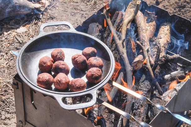 Falafel cook in a pan outdoors. Middle east culture. Prepared for grill on nature. Picnic in camping. Grilling season in nature open. - 写真・画像