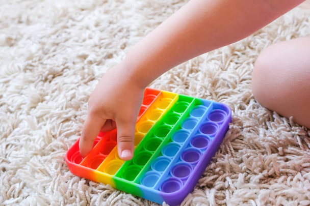 colorful antistress sensory toy fidget push pop it in kids hands. Kids play with pop it sensory toy. Stress and anxiety relief. Trendy silicon fidgeting game for stressed children and adults - 写真・画像