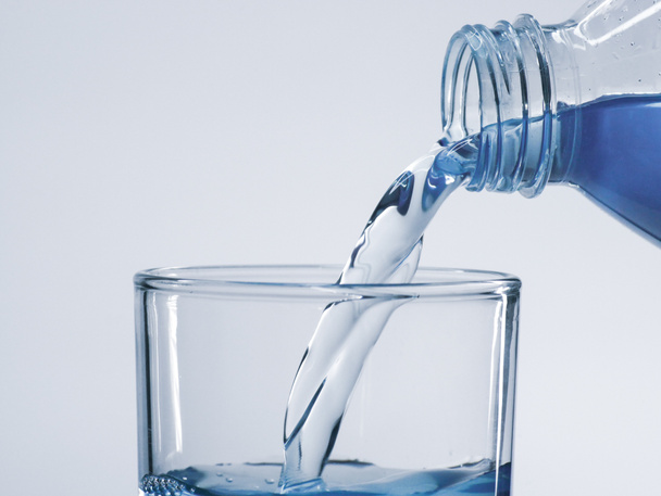 Versare acqua potabile pulita dalla bottiglia nel bicchiere. - Foto, immagini