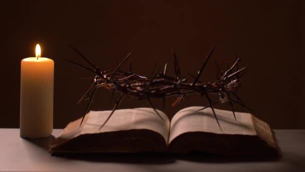 Die Bibel wird von einer Kerze mit Dornenkrone erleuchtet - Filmmaterial, Video