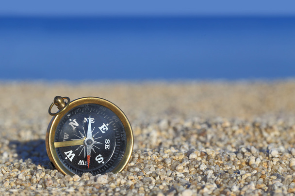 Старый компас на пляже с песком и морем
  - Фото, изображение