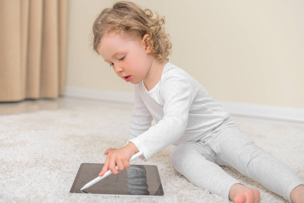Little girl draws or plays on the tablet computer. - Photo, image