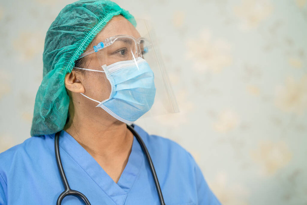 Médico asiático con protector facial y traje de PPE nuevo normal para comprobar el paciente proteger la infección de seguridad Brote de Coronavirus Covid-19 en la sala del hospital de enfermería de cuarentena. - Foto, Imagen