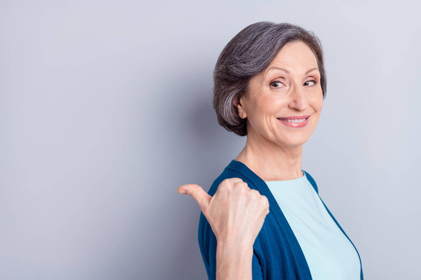 Photo portrait of smiling happy senior woman showing thumb blank space isolated on grey color background - 写真・画像