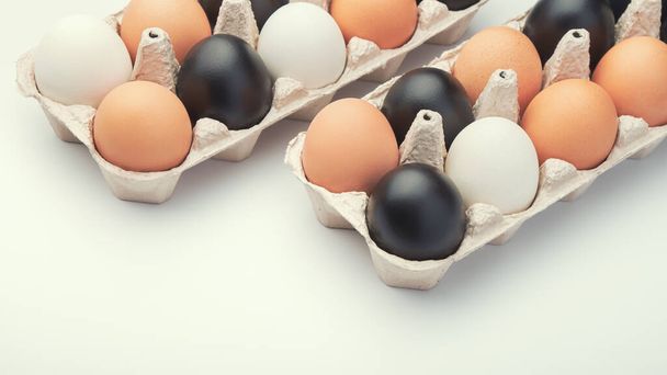 Karton kutularda farklı renkte yumurtalar. Siyah, beyaz ve kahverengi tavuk yumurtaları.. - Fotoğraf, Görsel