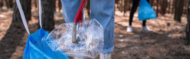 обрезанный вид волонтера, собирающего мусор в лесу, баннер - Фото, изображение