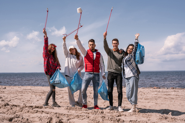gruppo di volontari allegri tenendo raccogliere strumenti e sacchetti della spazzatura  - Foto, immagini