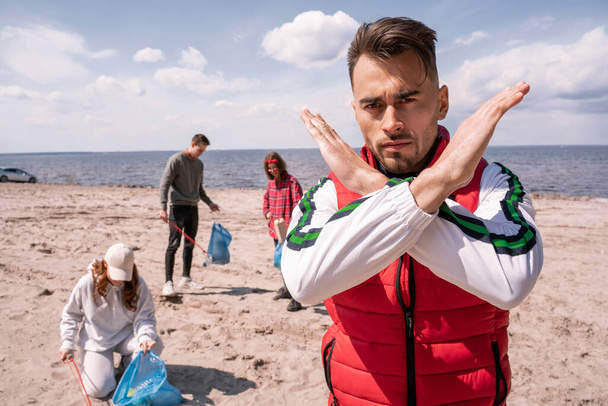 uomo mostrando fermare gesto vicino gruppo di volontari raccogliendo spazzatura, concetto di ecologia  - Foto, immagini