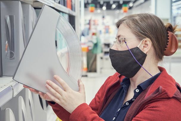 Woman wearing mask against the virus buys stand for folder of documents in store - Фото, зображення