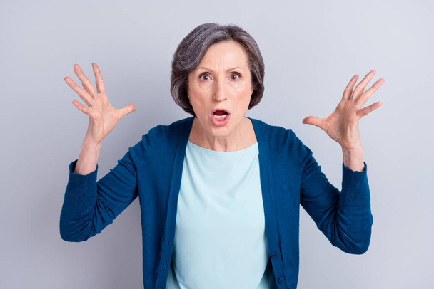 Photo of angry unhappy old woman raise hands bad mood wear blue cardigan isolated on grey color background - Foto, Imagem