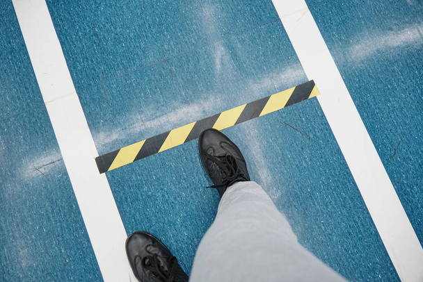 Мужские ноги ходят по синему полу в торговом центре. Границы, чтобы держать дистанцию. Крупный план - Фото, изображение