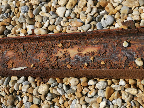 Oude roestige metalen balk of staal liggend over kiezelstrand - Foto, afbeelding