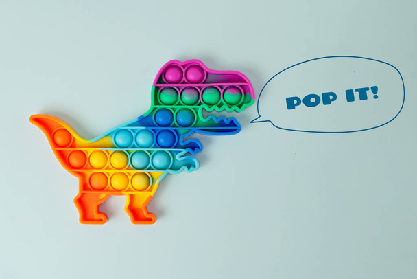 Nuevo juguete de silcone pop it en forma de dinosaurio en el fondo azul, con el dibujo growls.New juguete antiestrés sensorial para niños y adultos.. - Foto, imagen