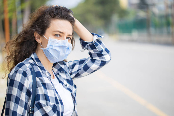 Jeune femme dans la rue portant un masque protecteur pour prévenir le coronavirus - Photo, image