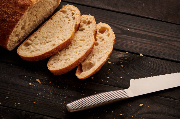 Świeżo upieczony domowy tartinowy chleb na ciemnym drewnianym stole - Zdjęcie, obraz