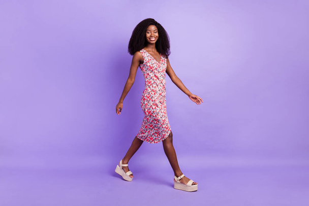 Full length body size side profile photo of smiling girl wearing long printed dress sandals isolated pastel purple color background - 写真・画像
