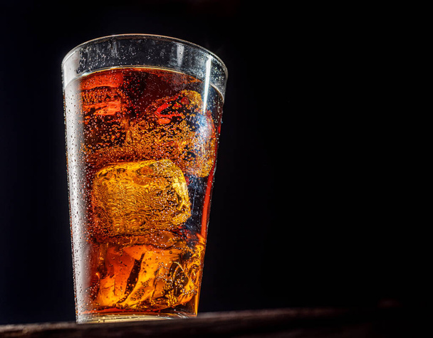 Chilled glass of cola drink with ice cubes isolated on dark background. - Фото, изображение
