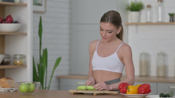 Donna sana taglio cetriolo mentre in piedi in cucina - Filmati, video