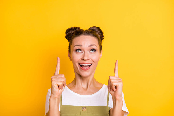 Portrait of attractive cheerful girl demonstrating up copy space offer ad solution isolated over bright yellow color background - Foto, Imagen