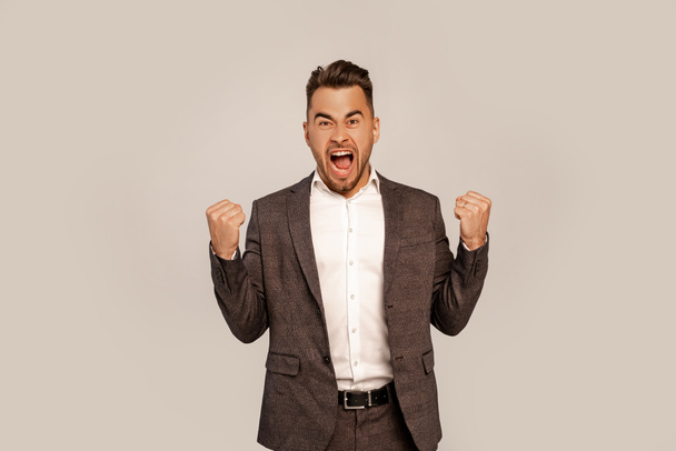 excited man shouting while showing yeah gesture isolated on grey - Foto, Imagen