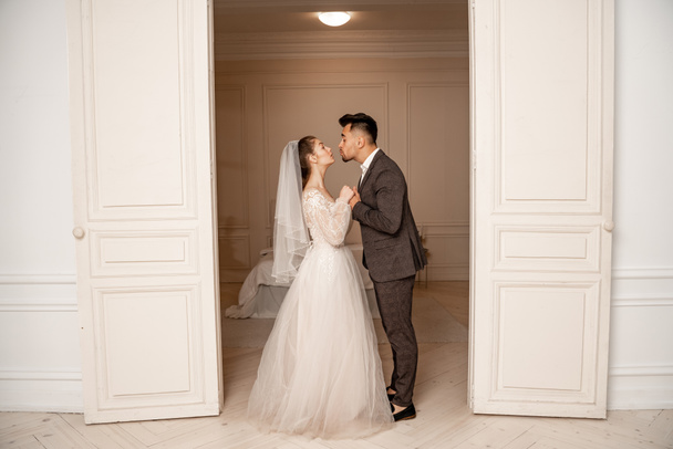 full length view of young newlyweds holding hands near entrance to bedroom - Foto, immagini